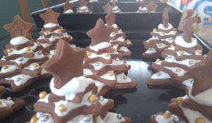 A whole batch of completed gingerbread Christmas trees with icing as snow