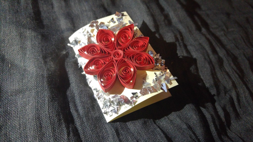 A handmade gift tag - red poinsettia flower surrounded with bits of silver foil
