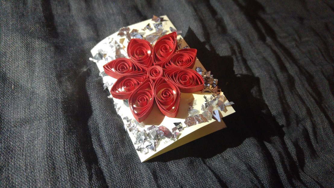 A handmade gift tag - red poinsettia flower surrounded with bits of silver foil