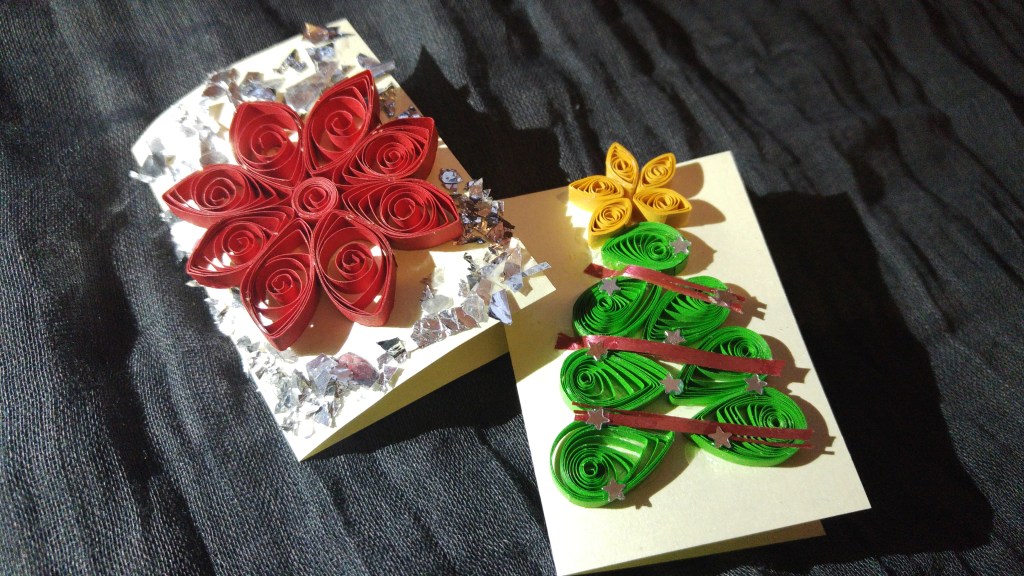 Two handmade quilled Christmas gift tags - a red flower and a Christmas tree with a star
