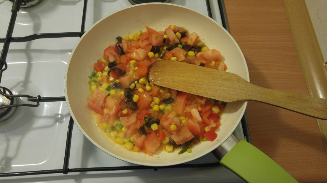Ingredients for a vegetable omelette on a frying pan on the hob