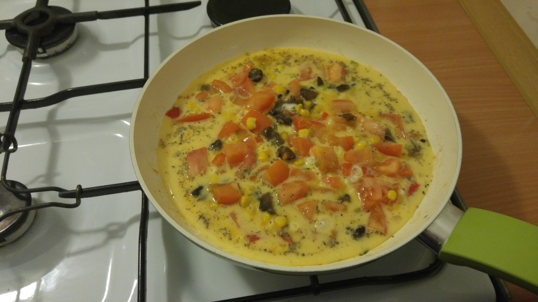 Vegetables and eggs on a frying pan on the hob