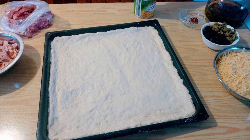 Pizza dough spread on a tray