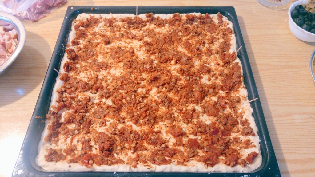 Pizza dough and tomato sauce on a baking tray