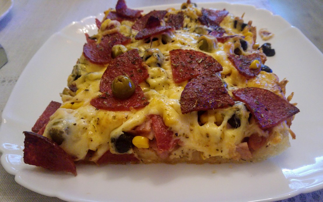 Slice of baked thick crust pizza