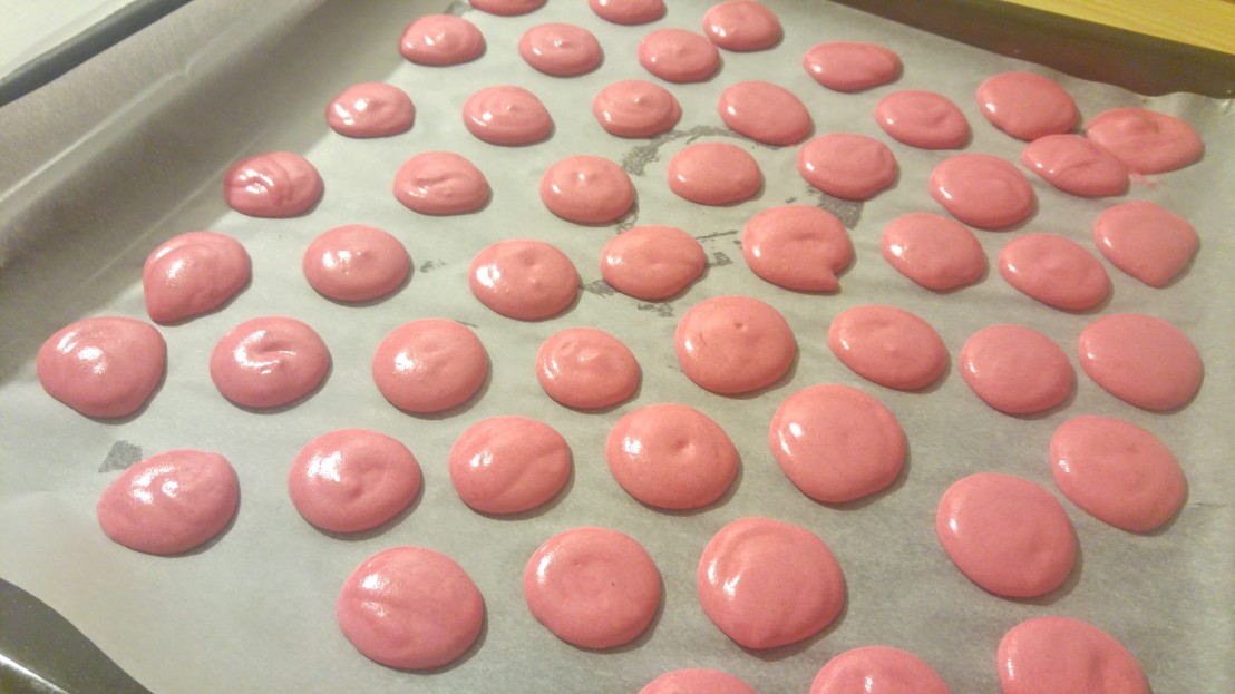 Pink round cookies on a baking tray before baking