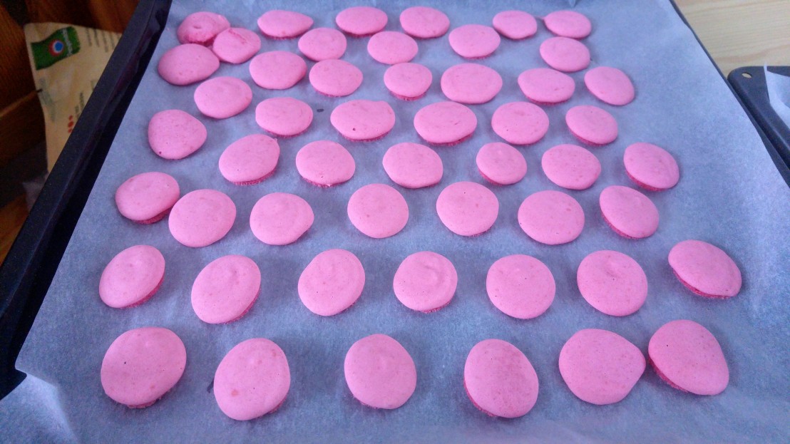 Baked pink small cookies on a baking tray