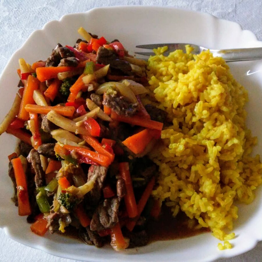 Chinese five spice stir fry on a plate, with yellow rice