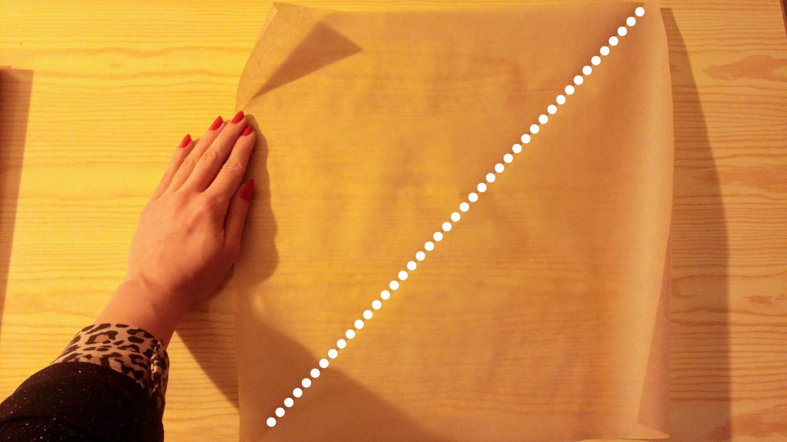 Dividing a square of baking paper into two triangles to make piping cones