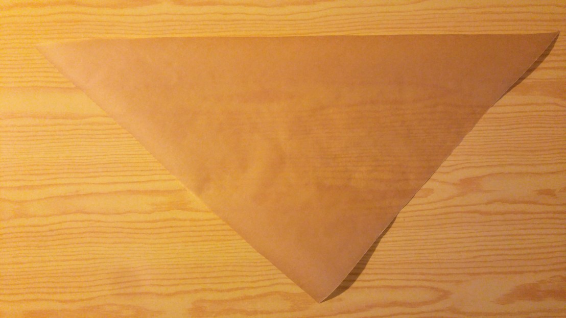 A triangle of paper that will be folded into a DIY piping cone