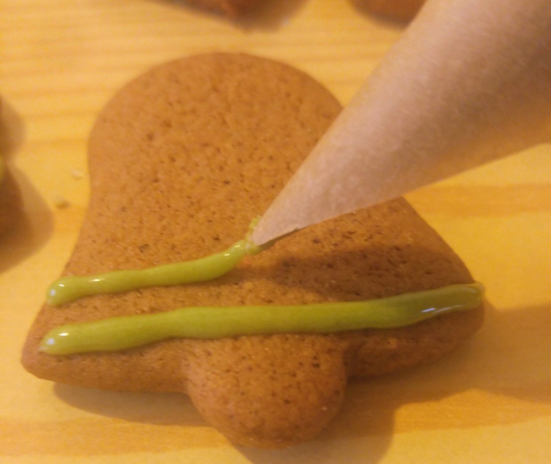 Decorating a gingerbread cookie with royal icing using a DIY piping cone