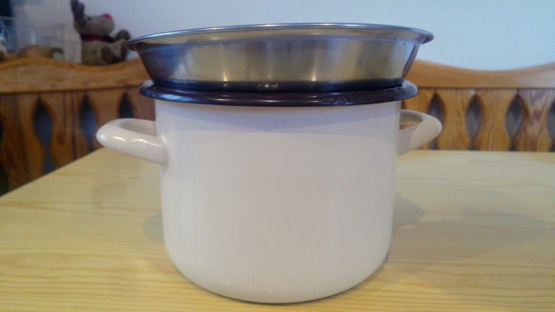 A metal bowl on top of a tall pot