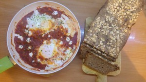 Cooked shakshuka in a pan and a loaf of sourdough bread