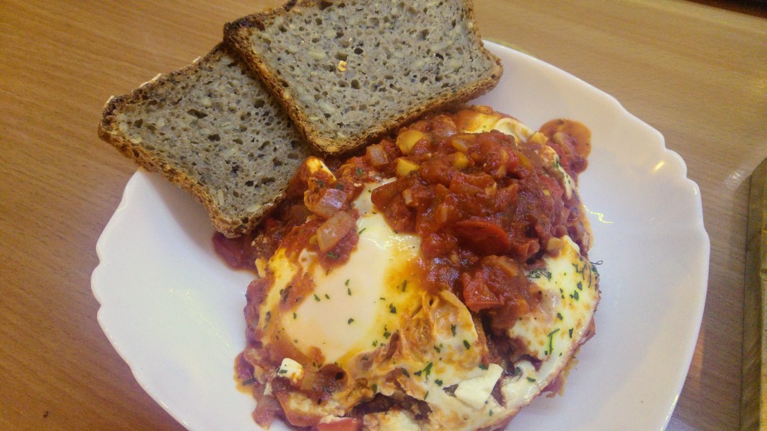 A portion of shakshuka on a plate and two slices of sourdough bread