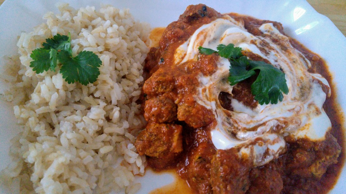 Chicken tikka masala served with rice, garnished with fresh coriander and yoghurt