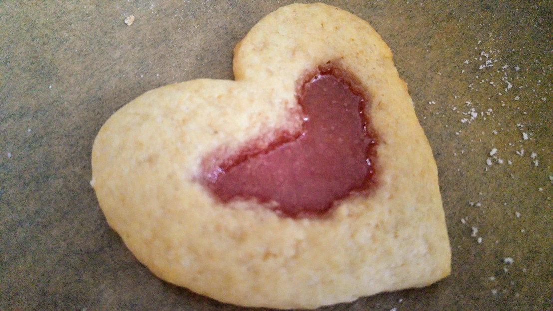 A baked, heart shaped stained glass cookie on a baking tray