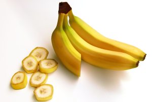 Three bananas next to banana slices