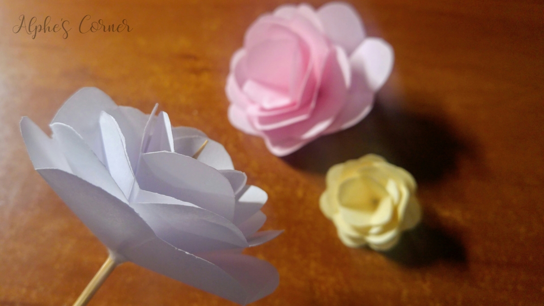 Three completed paper roses: white, yellow and pink