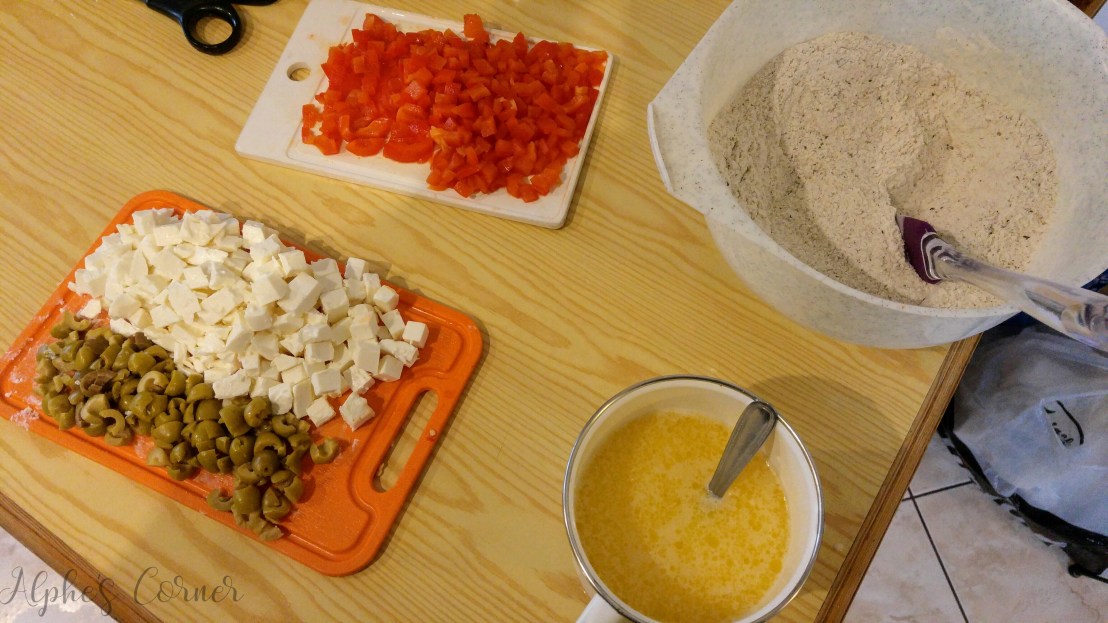 Chopped up feta cheese, olives and peppers and flour in a bowl