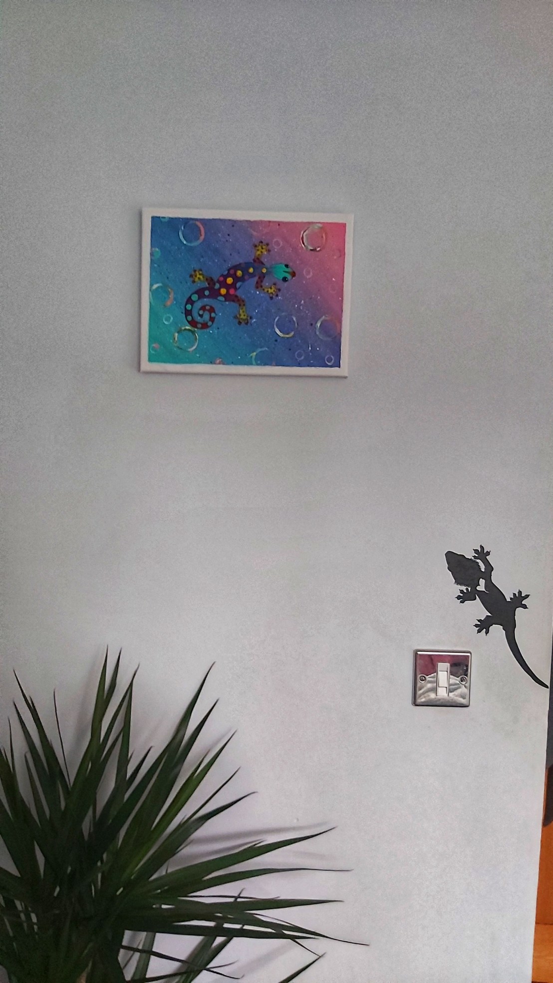 Acrylic gecko painting hanging on a wall