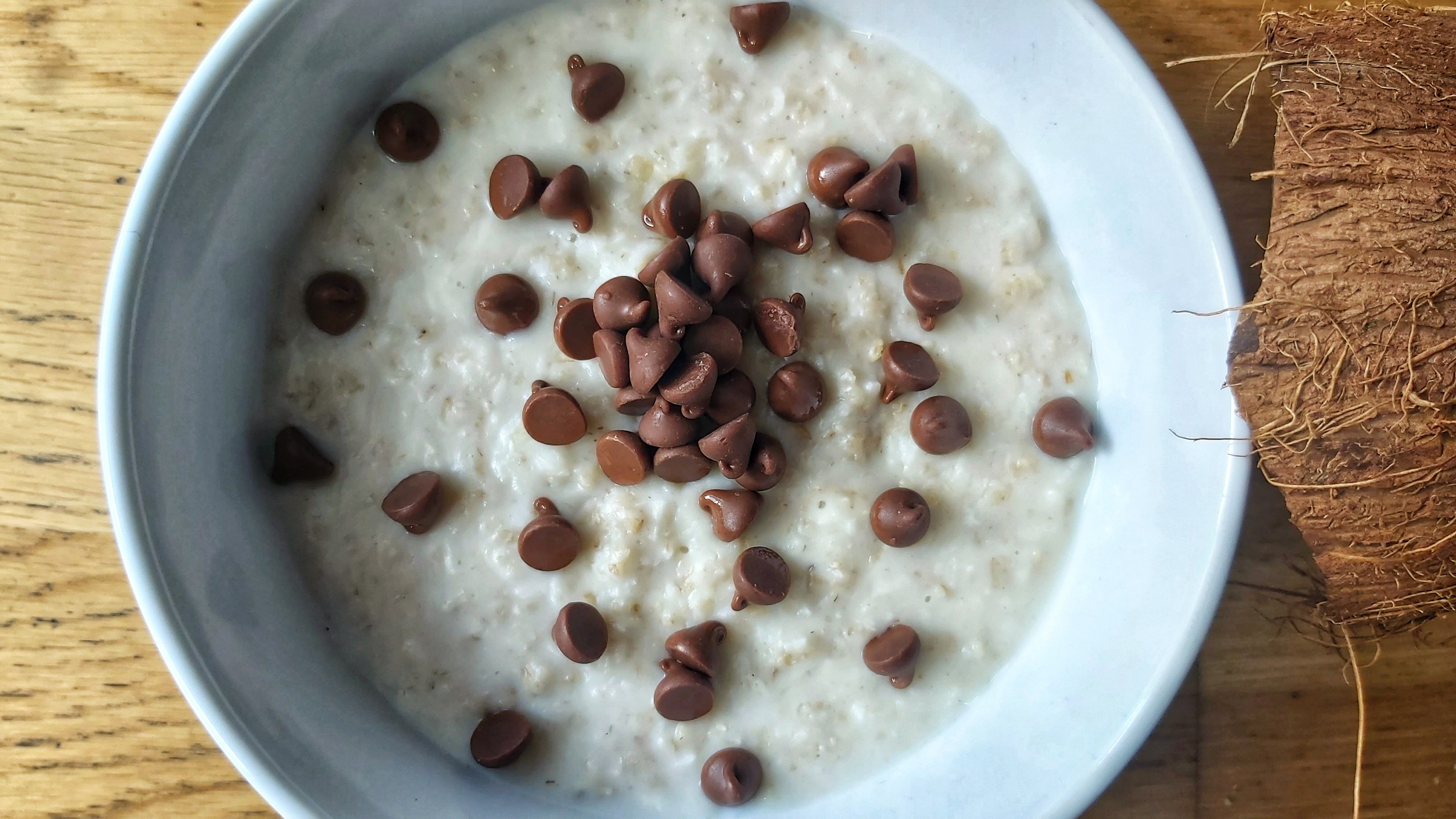 A bowl with coconut porridge with chocolate drops on top