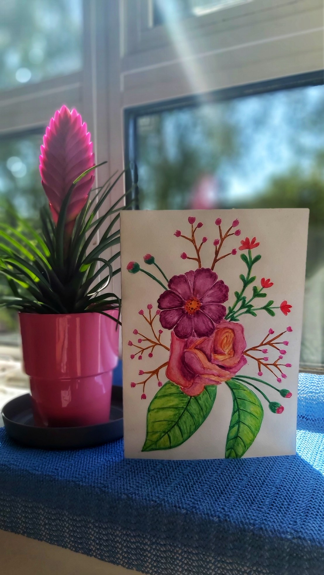 A floral watercolour card next to a flower