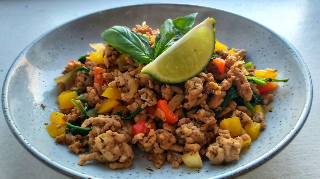 Zesty Thai Basil Pork on a plate, garnished with basil and lime