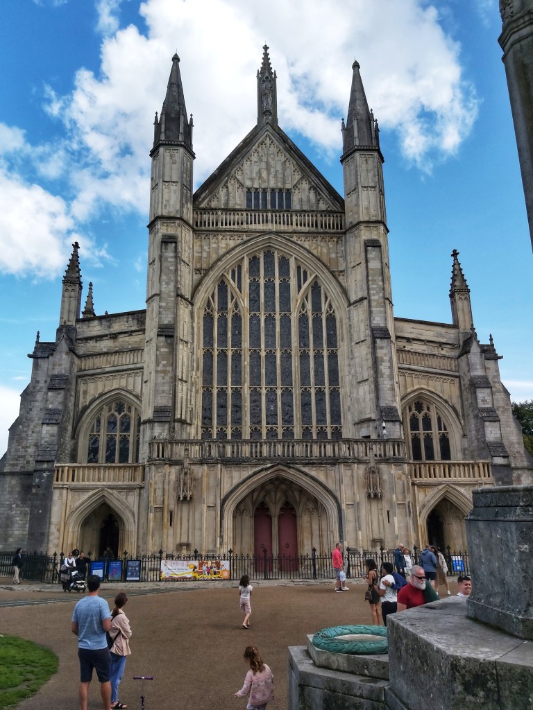 Winchester Cathedral viewed from the front, outside. Blue skies and a lot of tourists.