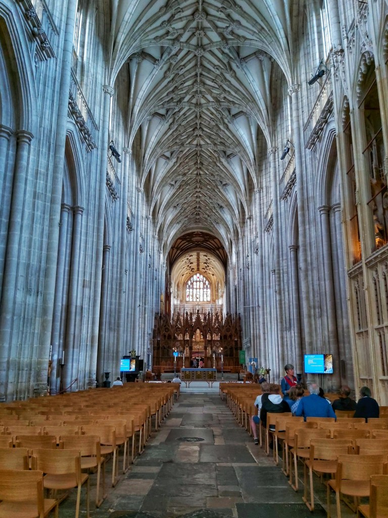 Winchester Cathedral viewed from the inside. High arched ceilings, rows of seats and the altar far at the back.