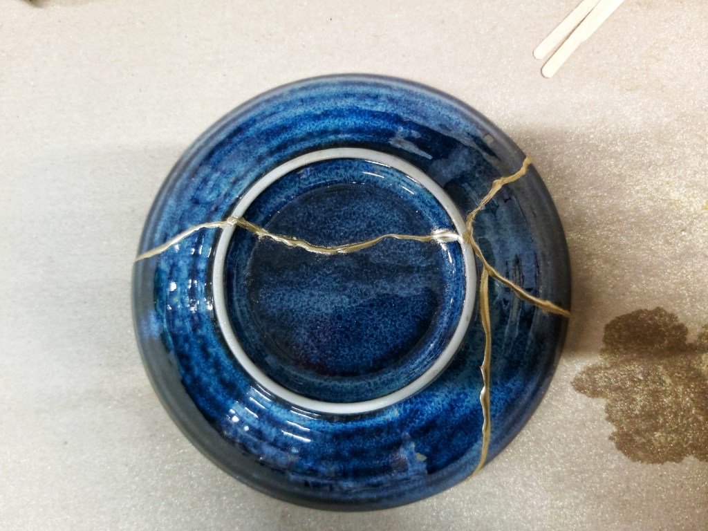 Ceramic bowl pieced together with kintsugi. Navy blue bowl with gold veins. View from the back.