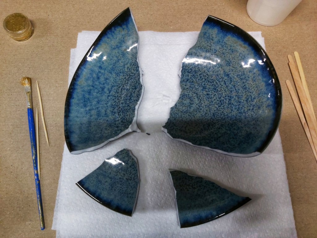 A navy blue ceramic bowl broken into four large pieces.