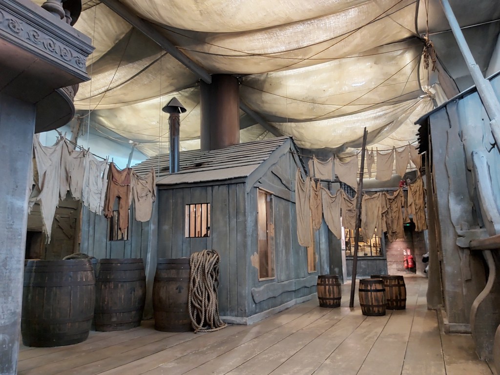 A room in the style of an old ship deck in Guildhall Museum in Rochester. Wooden barrels, ropes and clothes drying on a line.