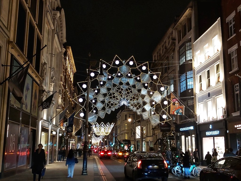 Christmas lights over a London road, at night.