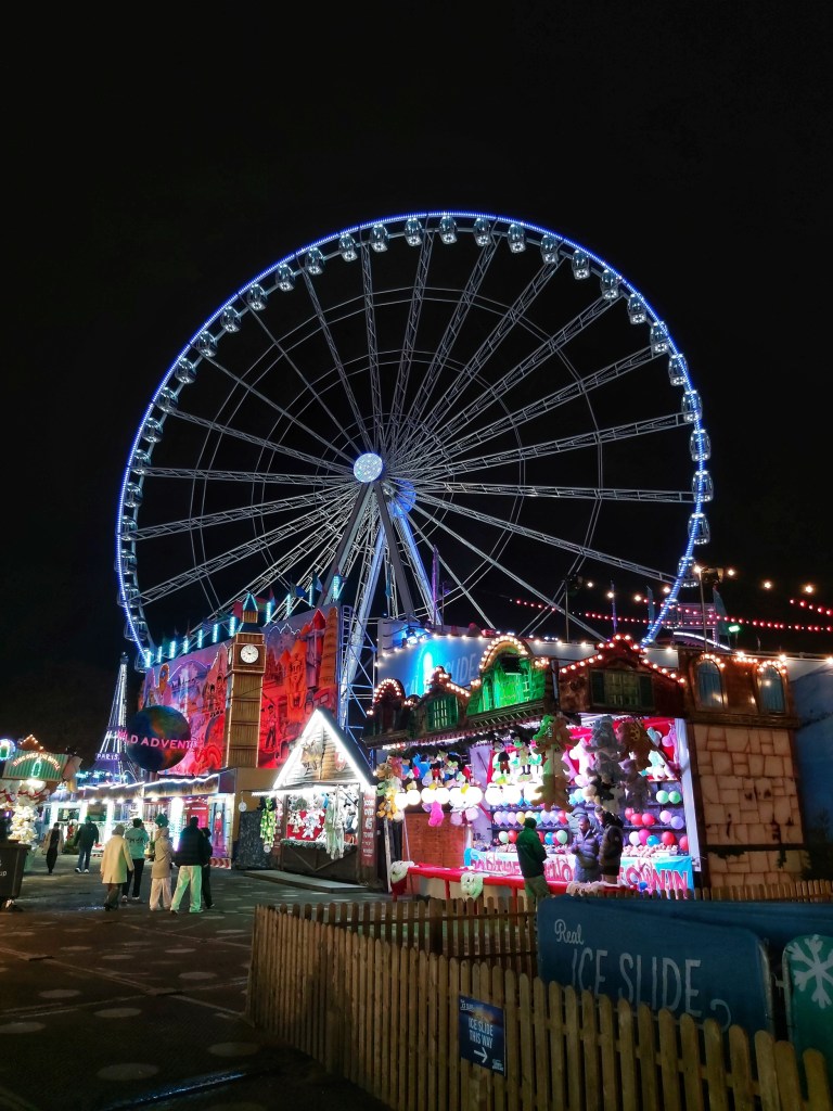 Christmas market and an illuminated ferris wheel in Winter Wonderland in Hyde Park, London
