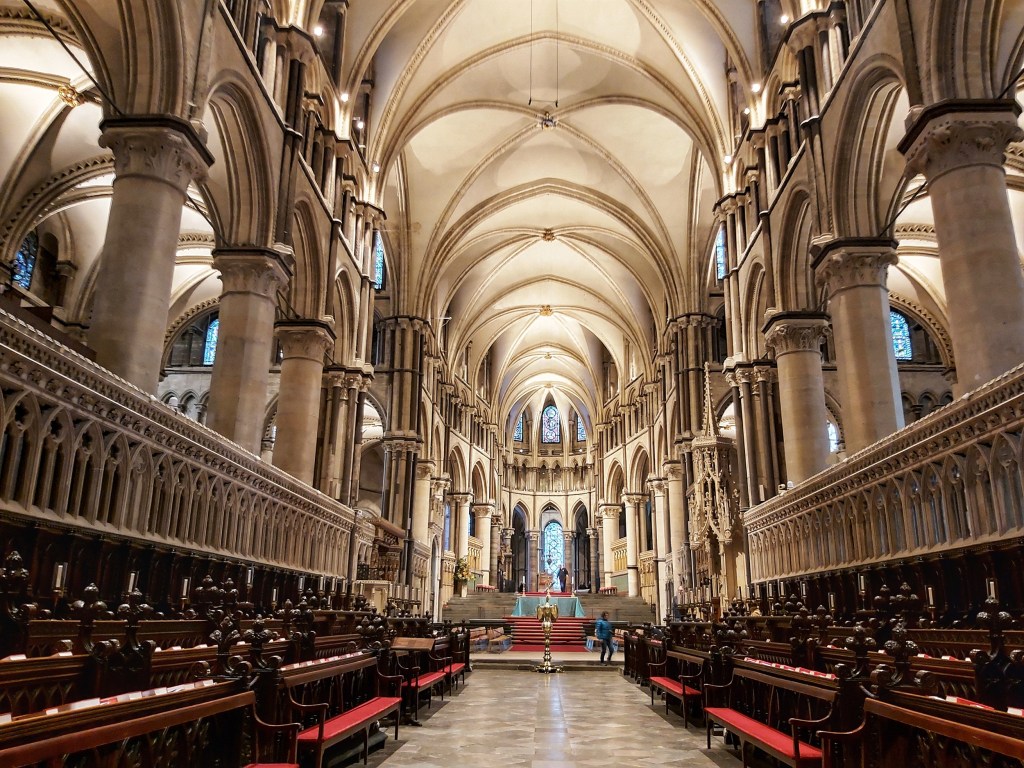 The inside of Canterbury Cathedral. Rows of seats, arched ceiling and the altar.