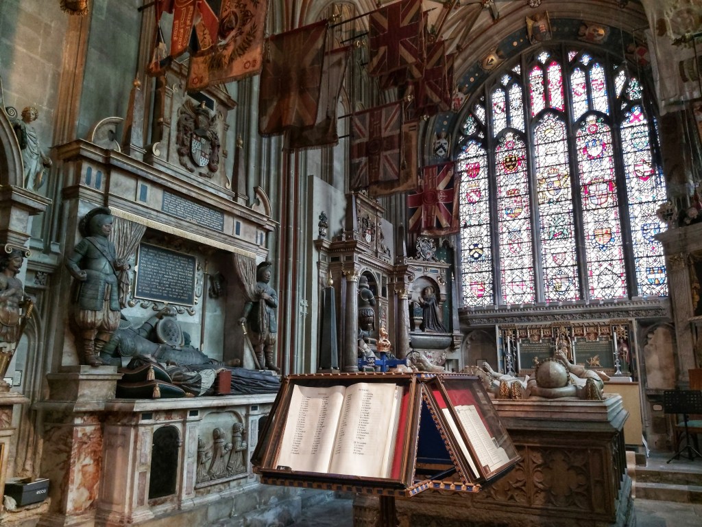 The inside of Canterbury Cathedral. Stained glass window, old flags, sculptures and medieval books.