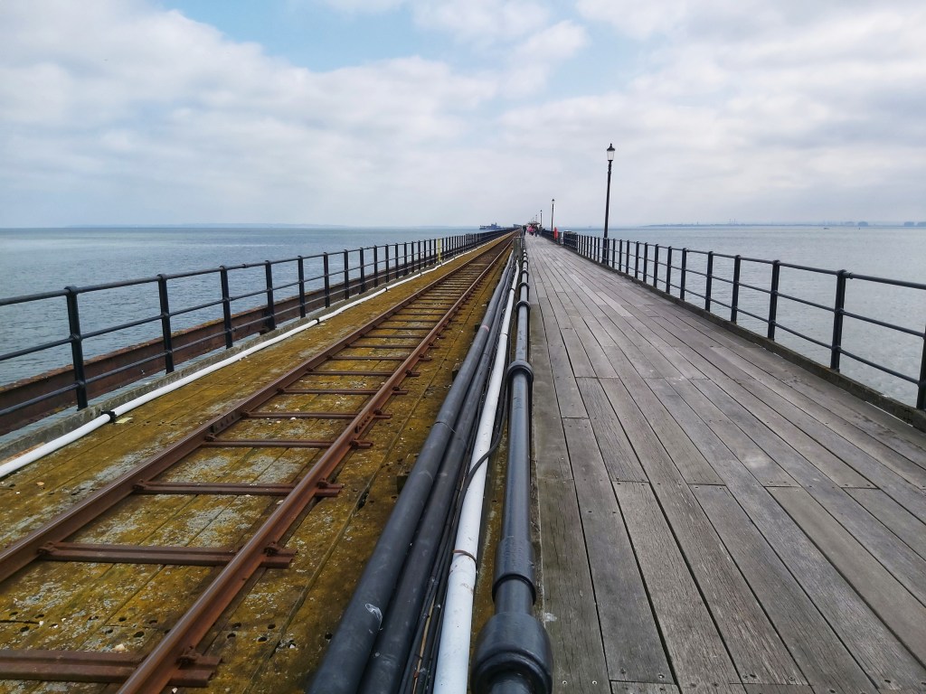 Southend Pier, measuring 1.33 miles. The pier has a wooden path for pedestrians and train tracks for shuttle trains running from the land to the end of the pier.