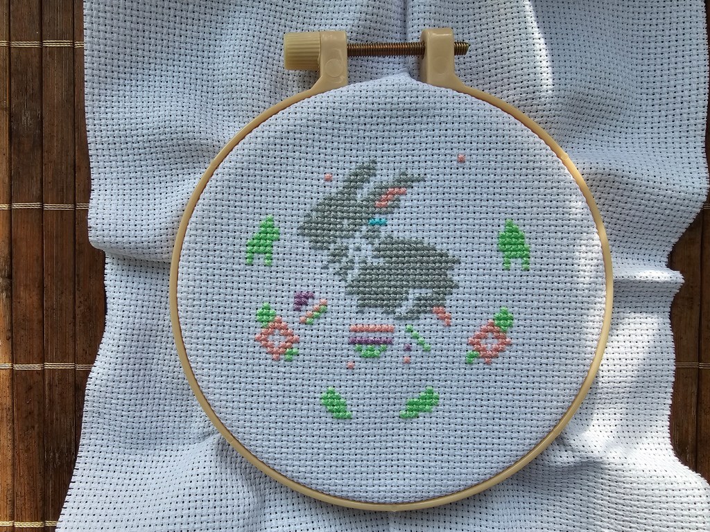 Partially completed Easter Bunny cross stitch project on a white aida, in a hoop.
