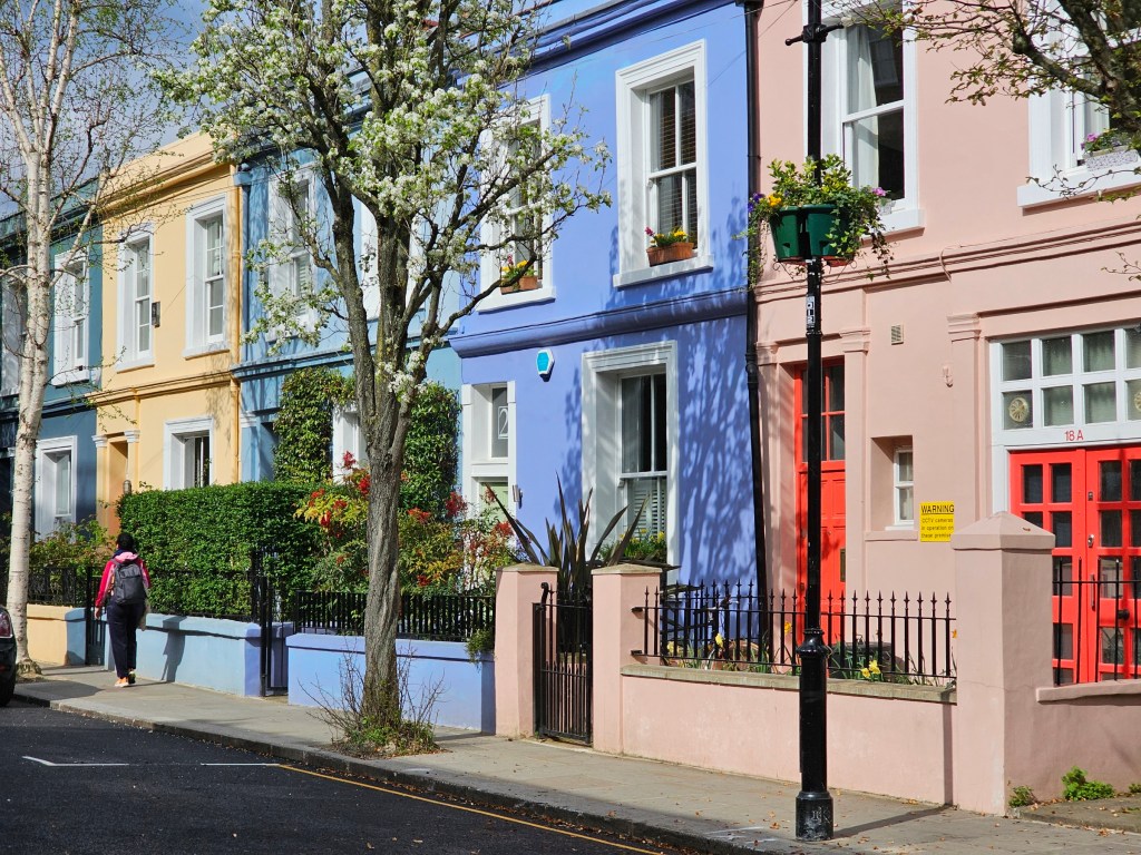 Pink, blue, yellow and green terraced houses on Portobello Road in Notting Hill, London.