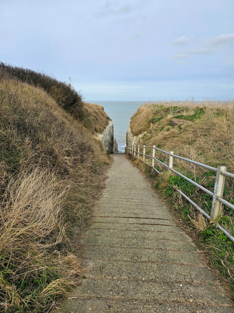 A narrow path from the top of a cliff down to the beach, cutting through the cliff. Photo taken near Botany Bay Beach in Kent, England.