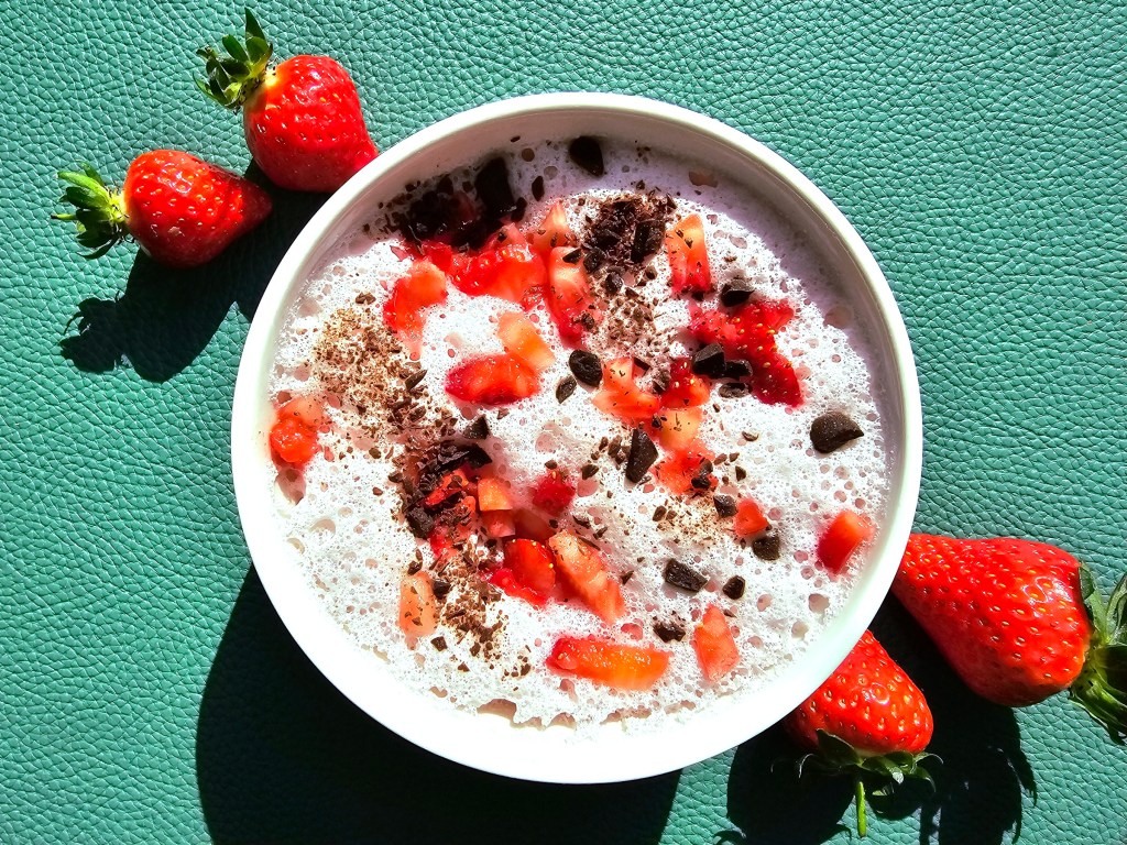 High Protein Strawberry Mousse in a bowl. Topped with fresh strawberries and dark chocolate.