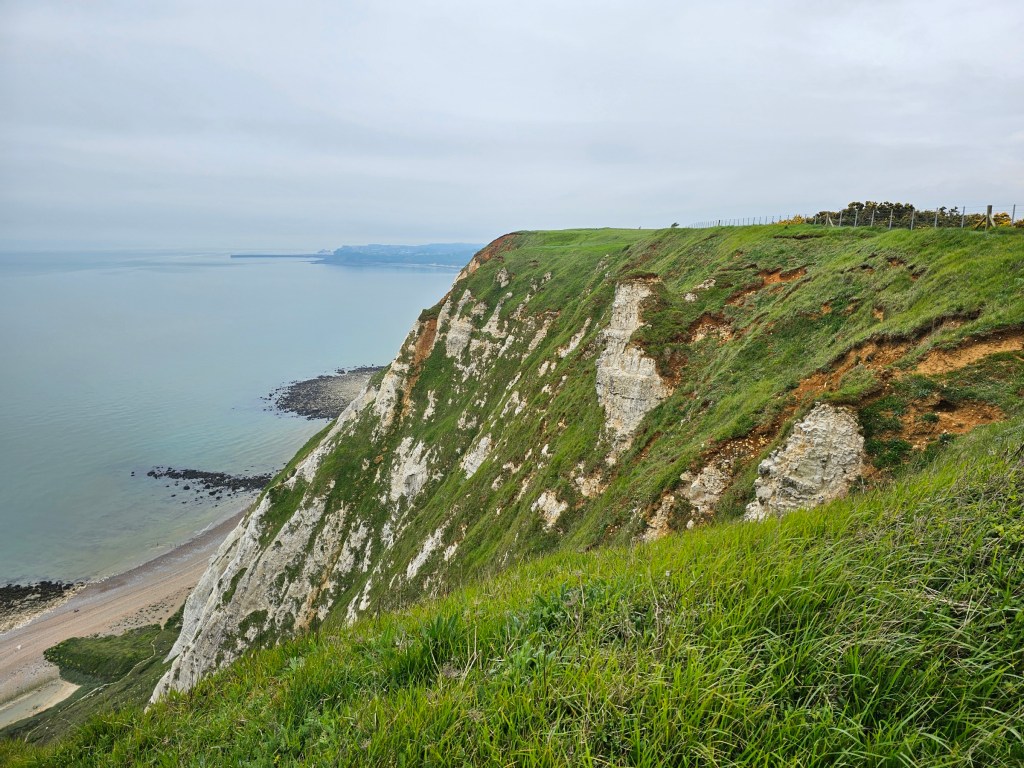 View from the top of a cliff between Folkestone and Dover. You can see the cliff and the sea underneath. Photo taken during overcast weather.