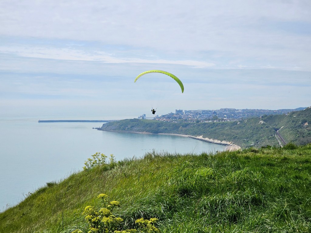 A person paragliding from the top of a cliff near Folkestone.