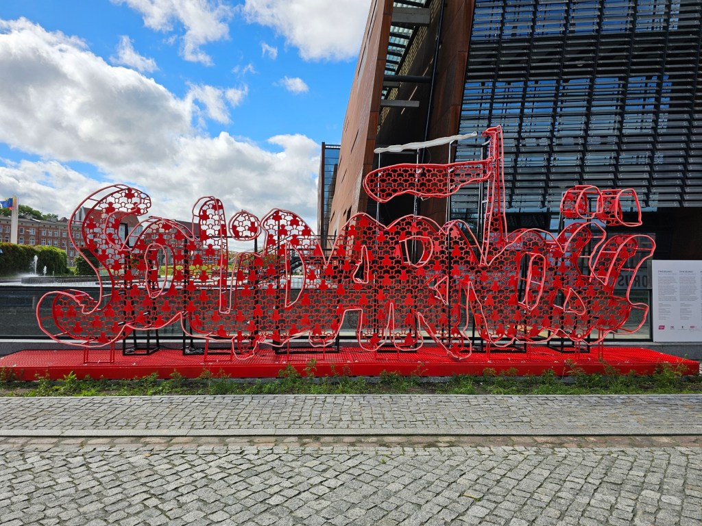 A sign made of metal wire, spelling Solidarność - Polish word for Solidarity. Photo taken in front of the European Solidarity Centre.