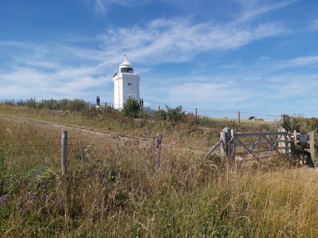 A former lighthouse on White Cliffs of Dover. A white building, surrounded by tall, sunburnt grass.