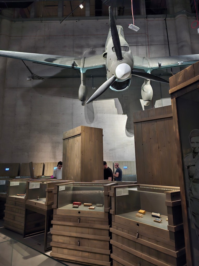 WWII Museum in Gdańsk. A warplane model hanging under the ceiling, and wooden crates with exhibits on the floor.