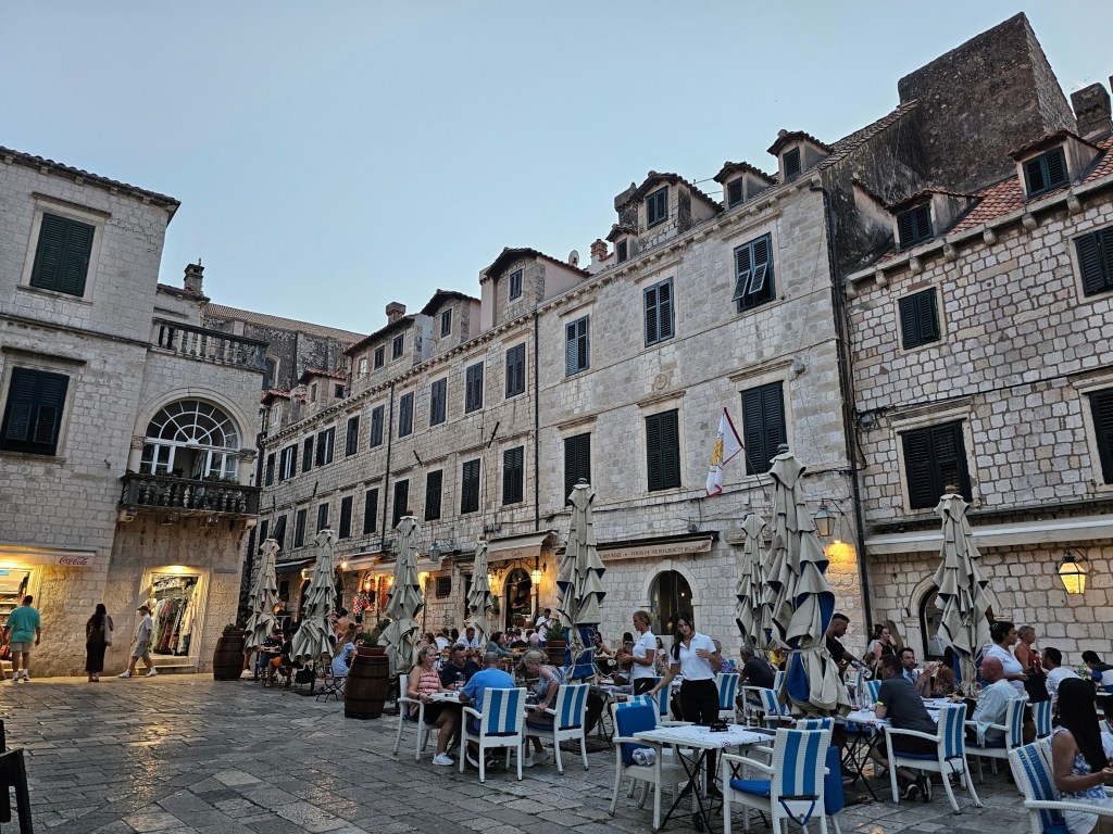 Dubrovnik Old Town in the evening. The light stone buildings are lit up.