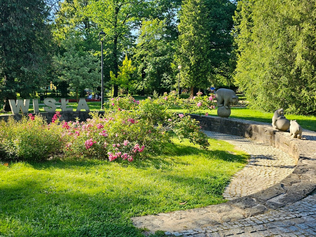 Iconic stone bear sculptures in the centre of Wisla, Poland. One bear is standing on top of a ball, and two smaller bear cubs are playing with a second ball. There are also stone letters spelling Wisla.