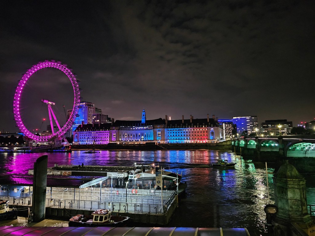 Illuminated London Eye and Westminster Bridge at night.