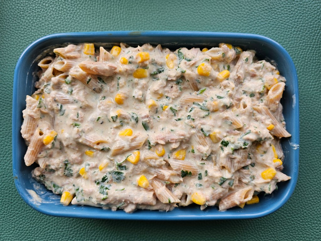 Healthy tuna and pasta bake with sweetcorn and parsley, sprinkled with low fat cheese, in an ovenproof dish prior to baking.